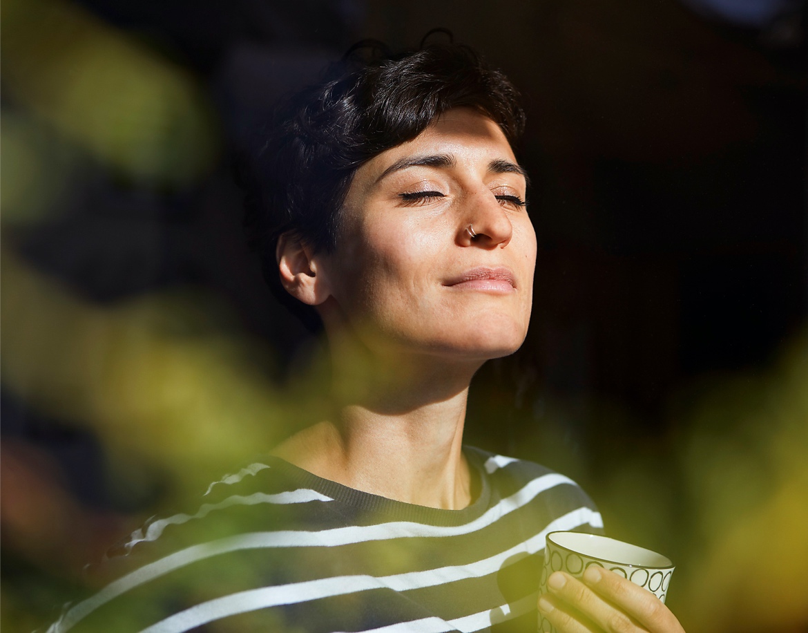 Eine Frau genießt den Sonnenschein und einen Kaffee