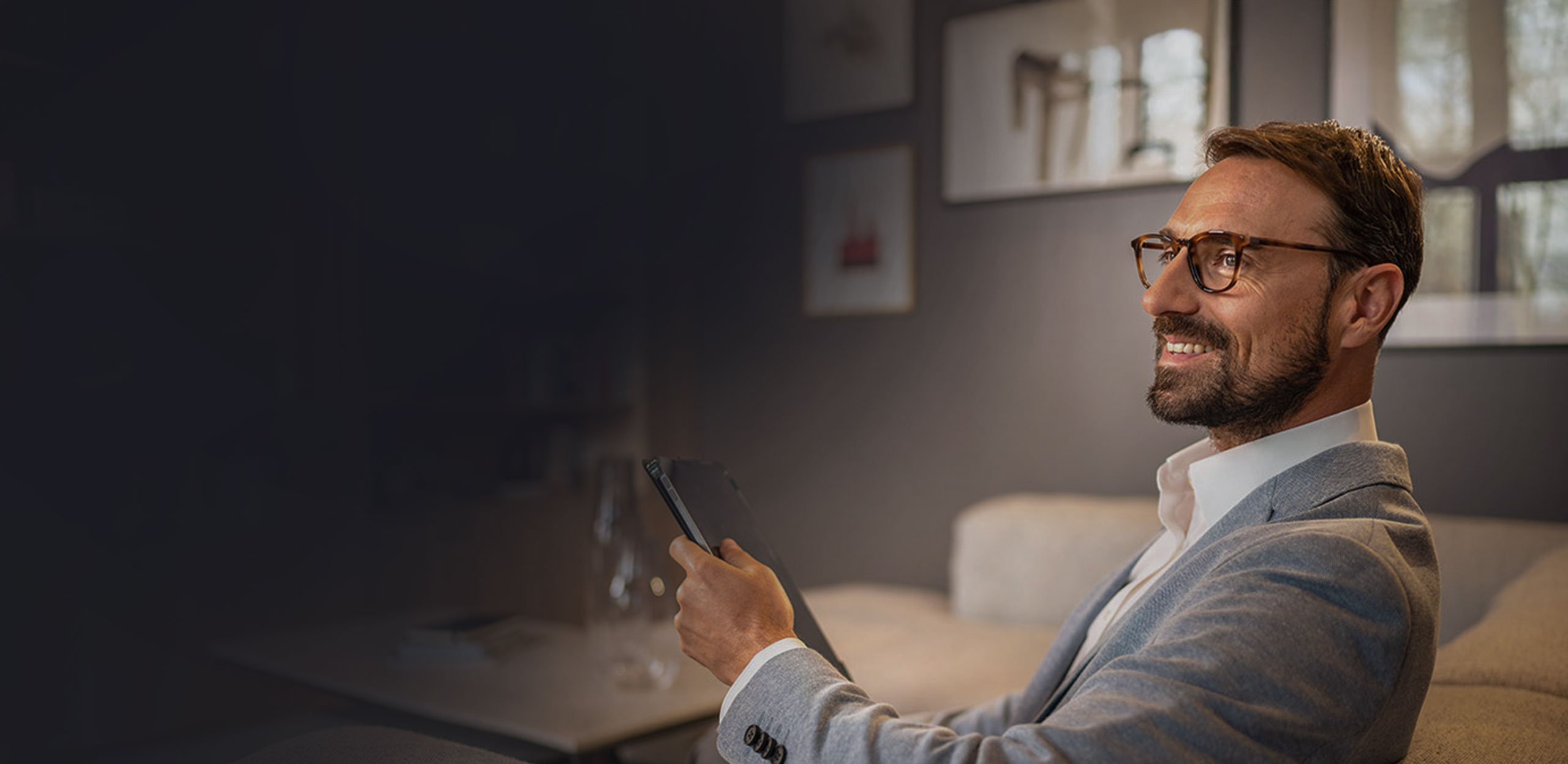 Mann sitzt mit einem Tablet auf einem Sofa